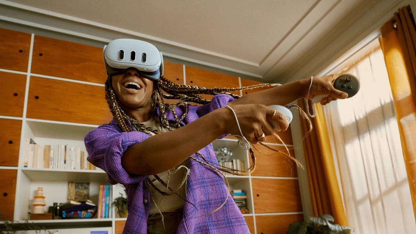 A woman laughing mid-swing in a Meta Quest 3 in her living room, both arms out with the controllers
