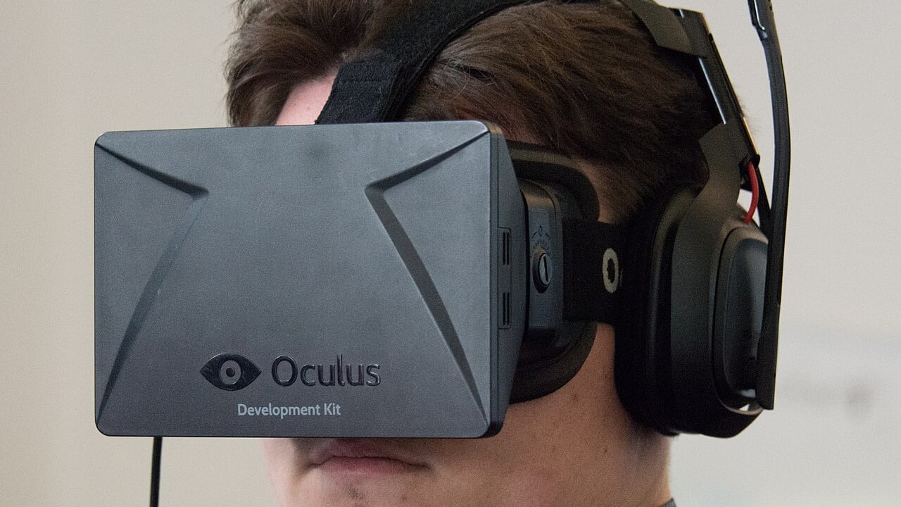 Palmer Luckey wearing a black Oculus Rift DK1 development kit and headphones at a 2014 VR meetup