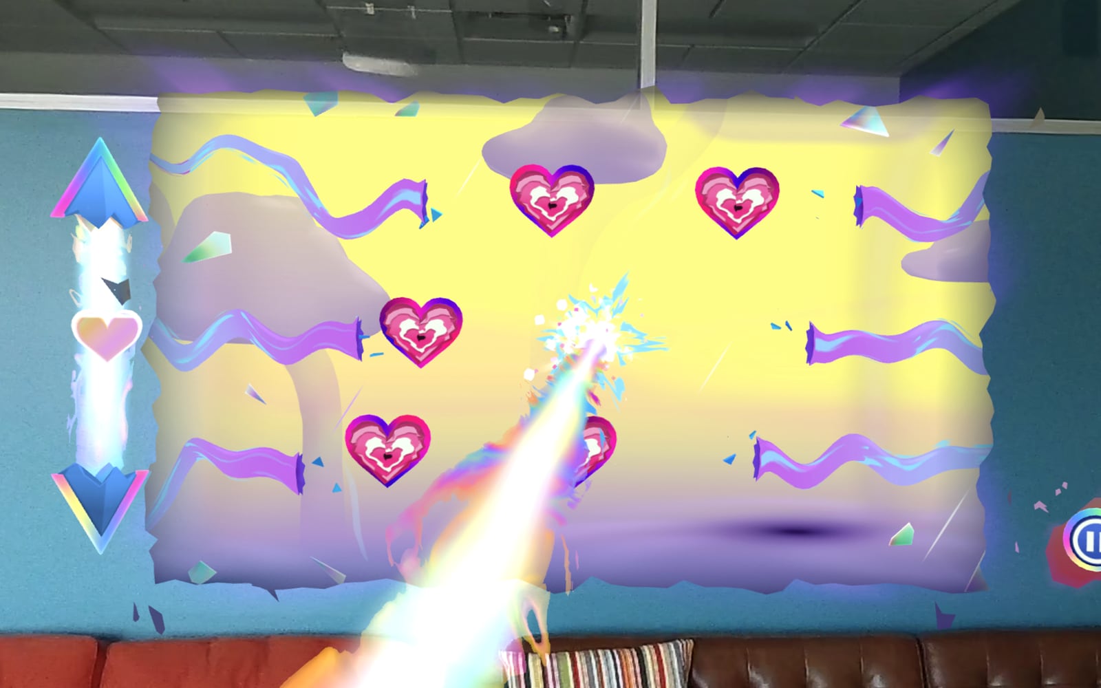 A Hyper Visor level hung on a blue office wall above a leather couch: a torn-edged yellow rift full of pink heart targets, with a rainbow energy beam firing from the player's hand